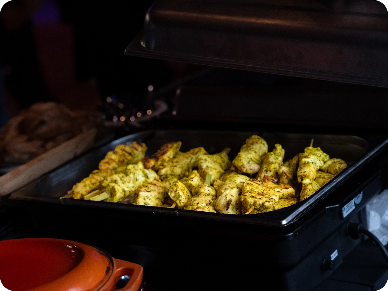 Grilled chicken skewers in a warming dish.